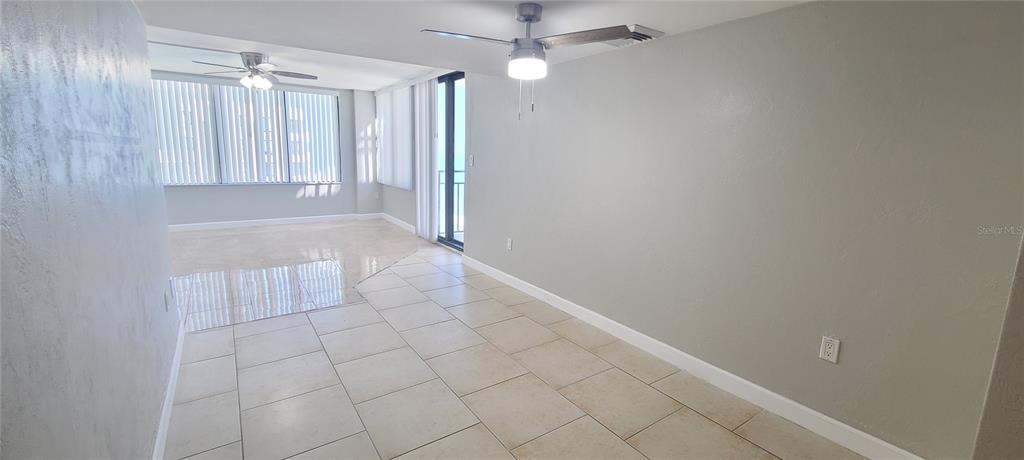 A bright, open-concept room features light-colored tile flooring, gray walls, and two ceiling fans — 3051 S ATLANTIC AVENUE UNIT 1904, DAYTONA BEACH SHORES, FL