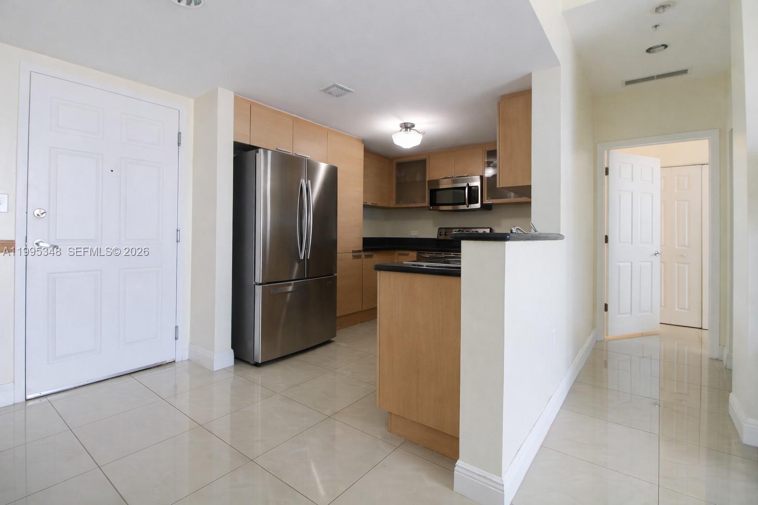 A kitchen features light wood cabinets, stainless steel appliances, and a black countertop peninsula — 140 S Dixie Hwy # 1019, Hollywood FL 33020, HOLLYWOOD, FL