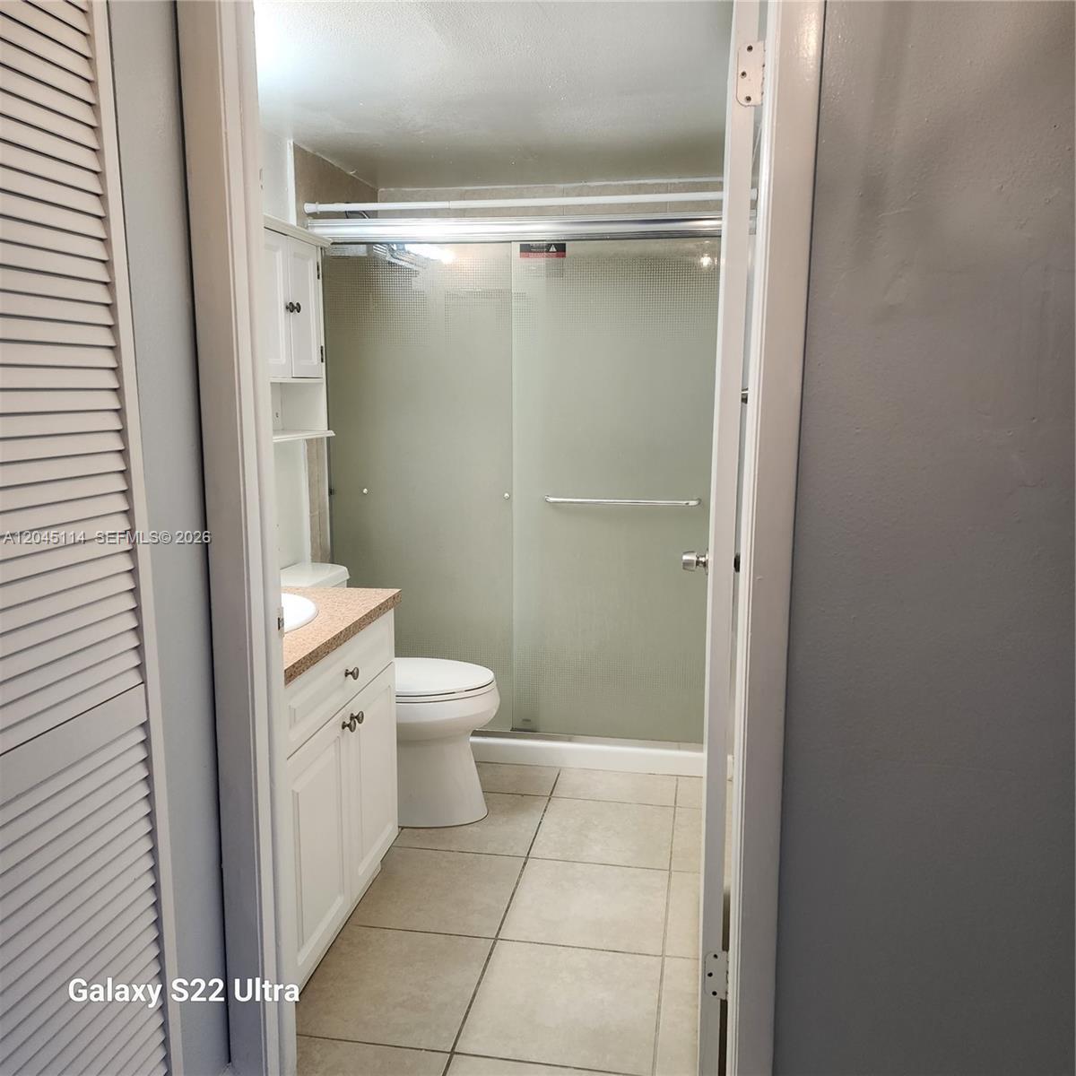 A bathroom features a white vanity, a toilet, and a glass-enclosed shower with tiled floors — 8200 SW 210th St # 111, Cutler Bay FL 33189, CUTLER BAY, FL