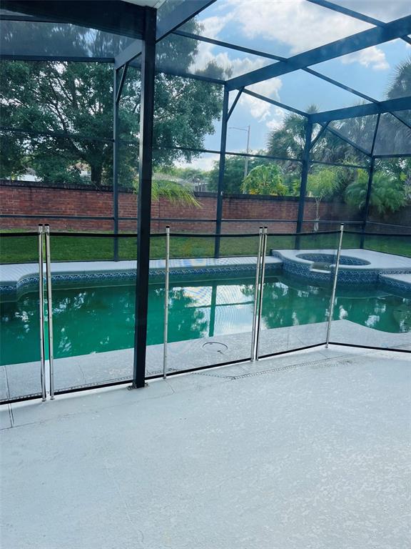 A swimming pool and hot tub are enclosed by a screen cage and safety fence — 5444 CREPE MYRTLE CIRCLE, KISSIMMEE, FL