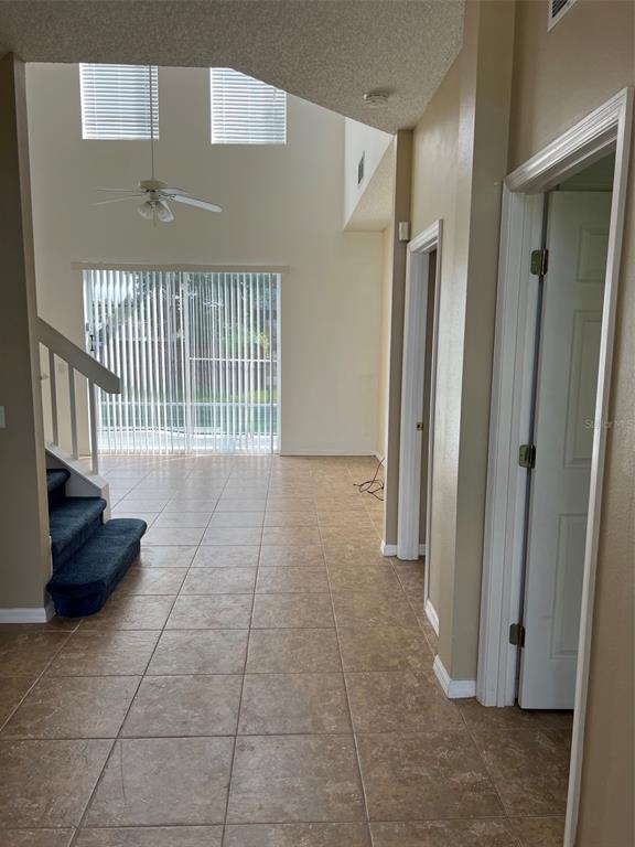 A tiled entryway leads to a living area with high ceilings, a staircase, and sliding doors — 5444 CREPE MYRTLE CIRCLE, KISSIMMEE, FL