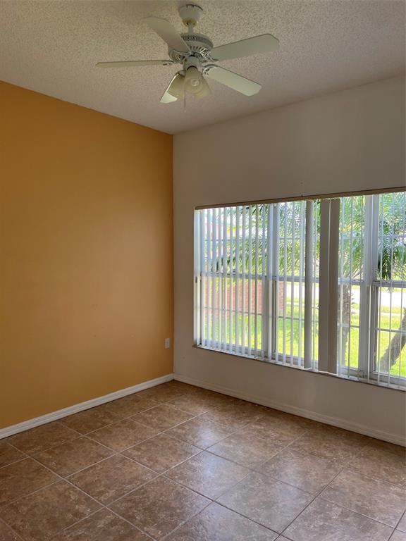 An empty room features tan tile flooring, an orange accent wall, and a ceiling fan — 5444 CREPE MYRTLE CIRCLE, KISSIMMEE, FL