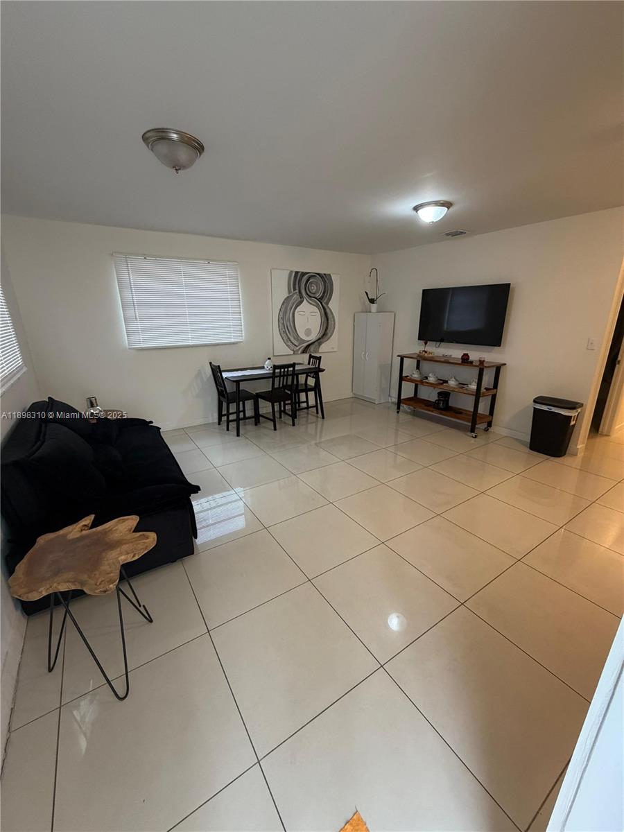 A living room features white tile floors, a black sofa, a dining set, and a television — 1132 NW 38th St # 1132, Miami FL 33127, MIAMI, FL