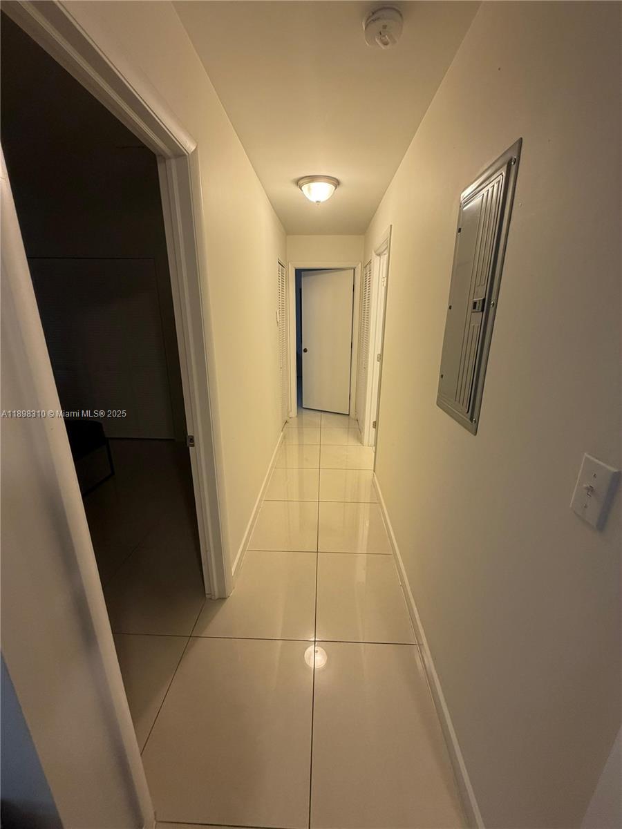 A narrow hallway features light-colored floor tiles, white walls, and a metal electrical panel — 1132 NW 38th St # 1132, Miami FL 33127, MIAMI, FL