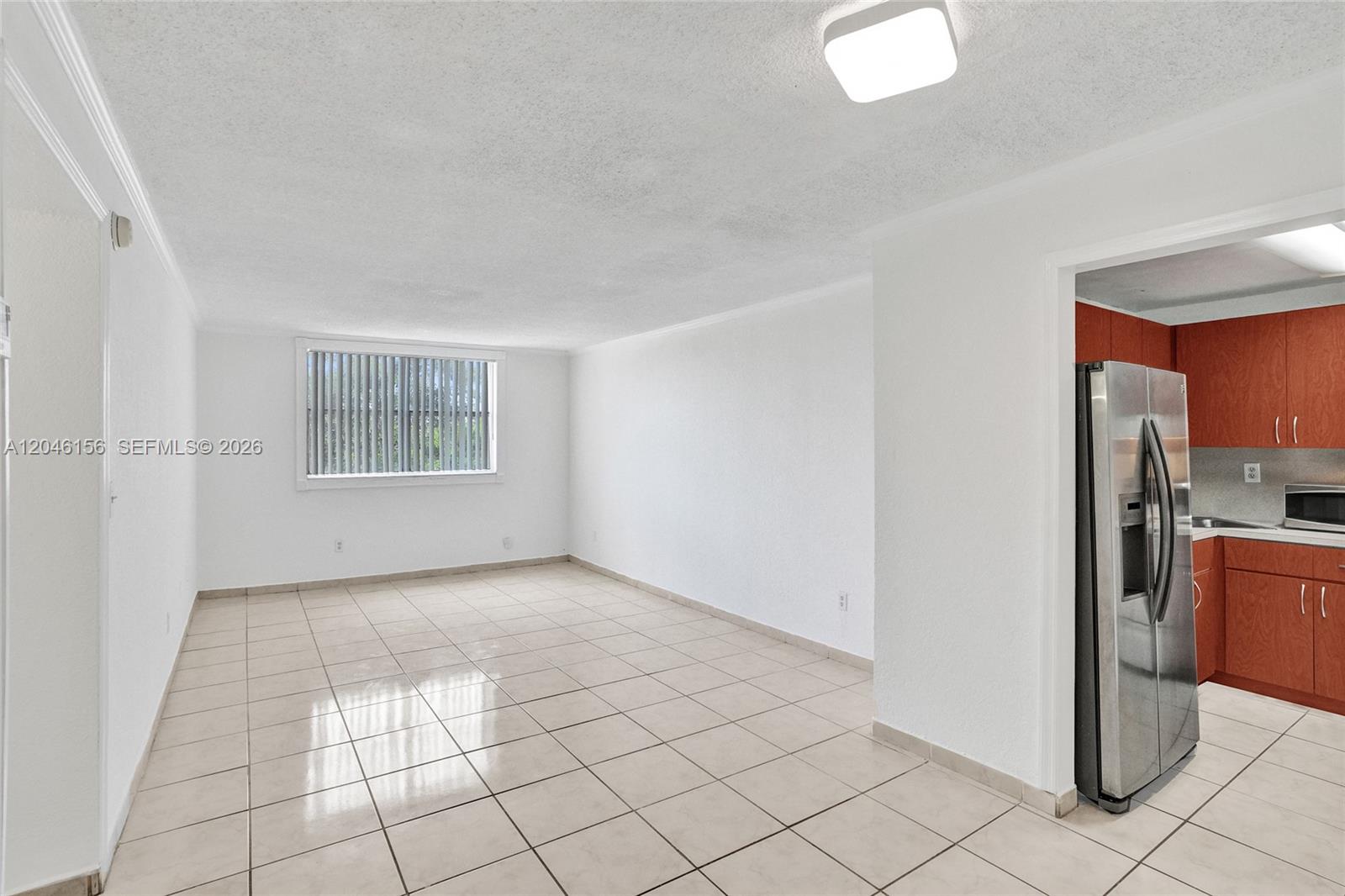 A bright, tiled living area opens into a kitchen with wood cabinets and stainless appliances — 606 W 81st St # 323, Hialeah FL 33014, HIALEAH, FL