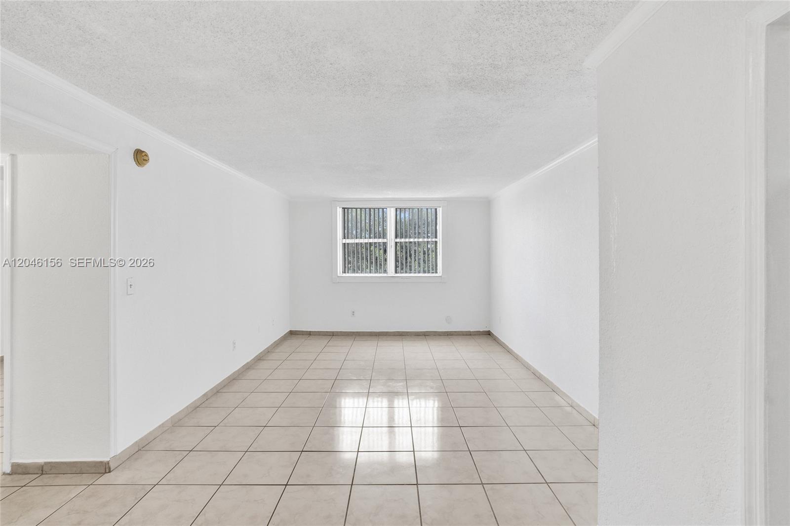 An empty room features white walls, a single window, and light-colored square floor tiles — 606 W 81st St # 323, Hialeah FL 33014, HIALEAH, FL