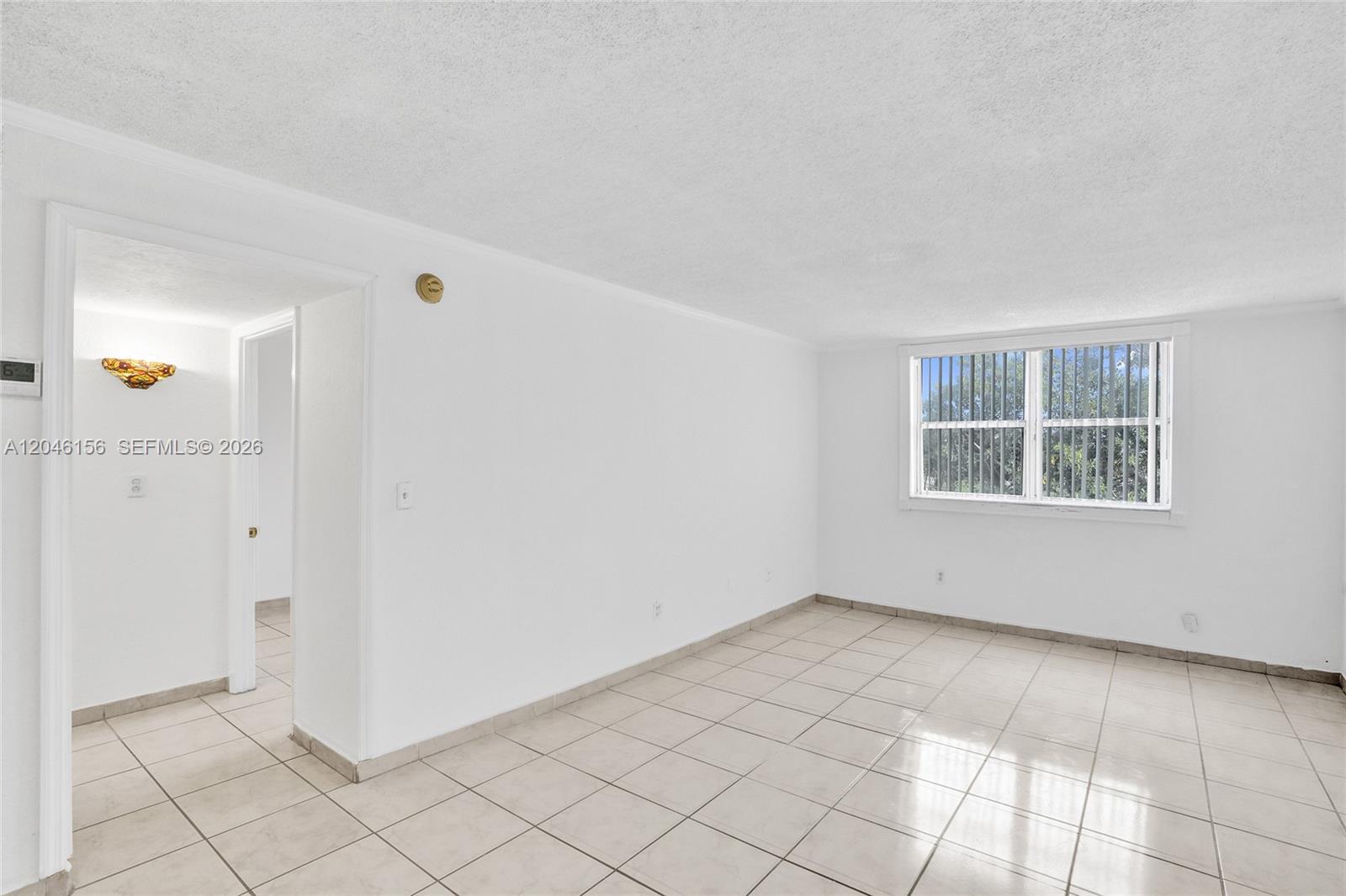 An empty room features white walls, light-colored tile flooring, and a single window — 606 W 81st St # 323, Hialeah FL 33014, HIALEAH, FL
