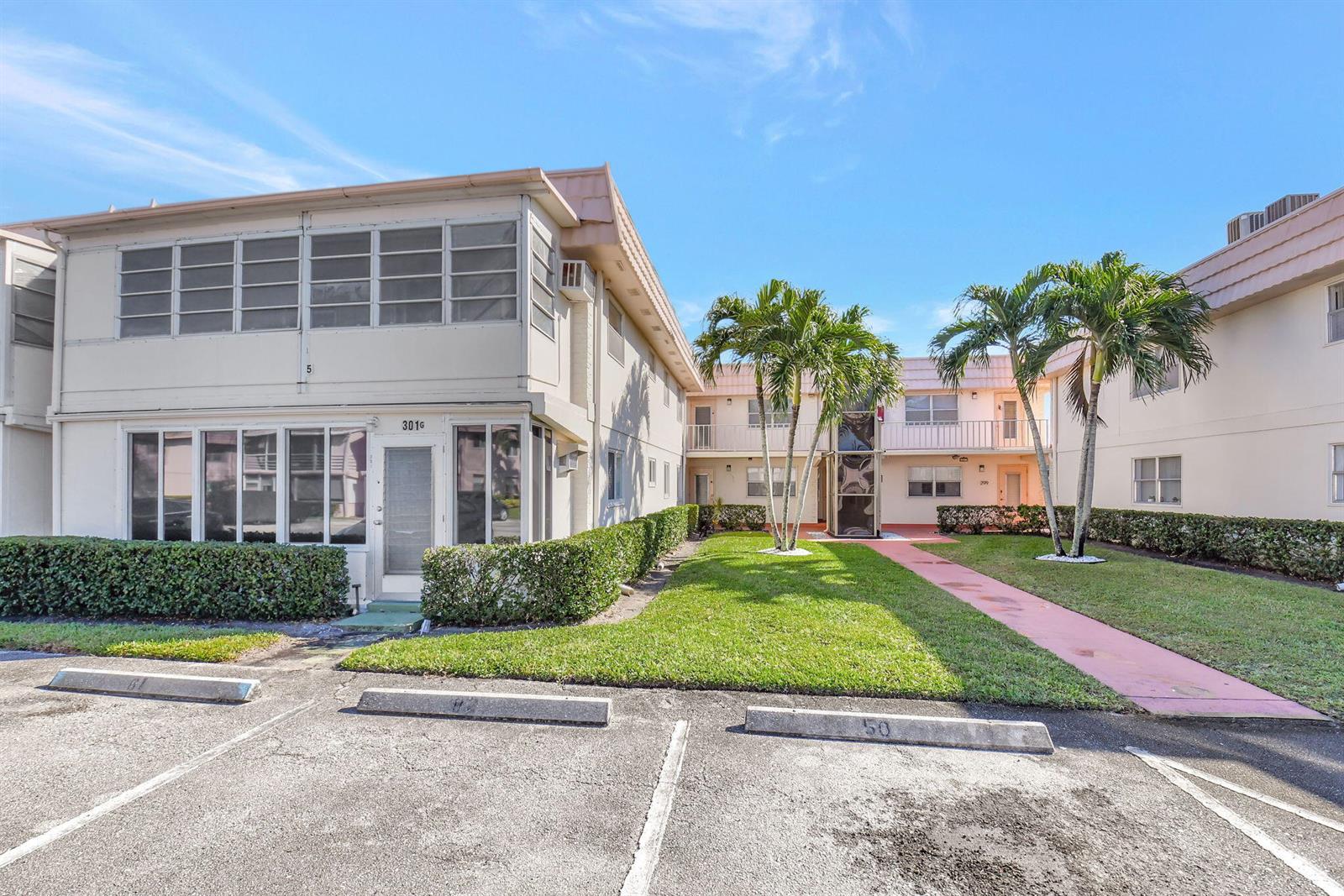 A two-story apartment building with a parking lot and a grassy courtyard with palm trees — 325 Saxony G, Delray Beach FL 33446, DELRAY BEACH, FL