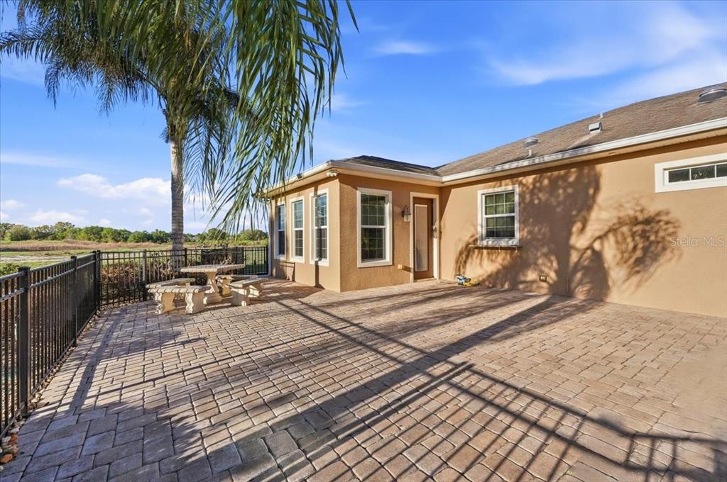 A paved patio with a stone table and benches sits beside a tan house exterior — 576 MEANDERING WAY, POLK CITY, FL