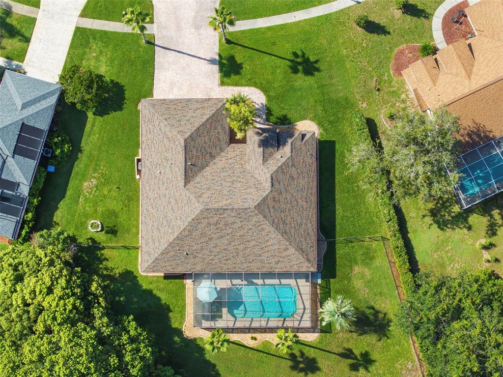An aerial view shows a house with a shingled roof, a screened pool, and landscaping — 14207 CORNEWALL LANE, SPRING HILL, FL