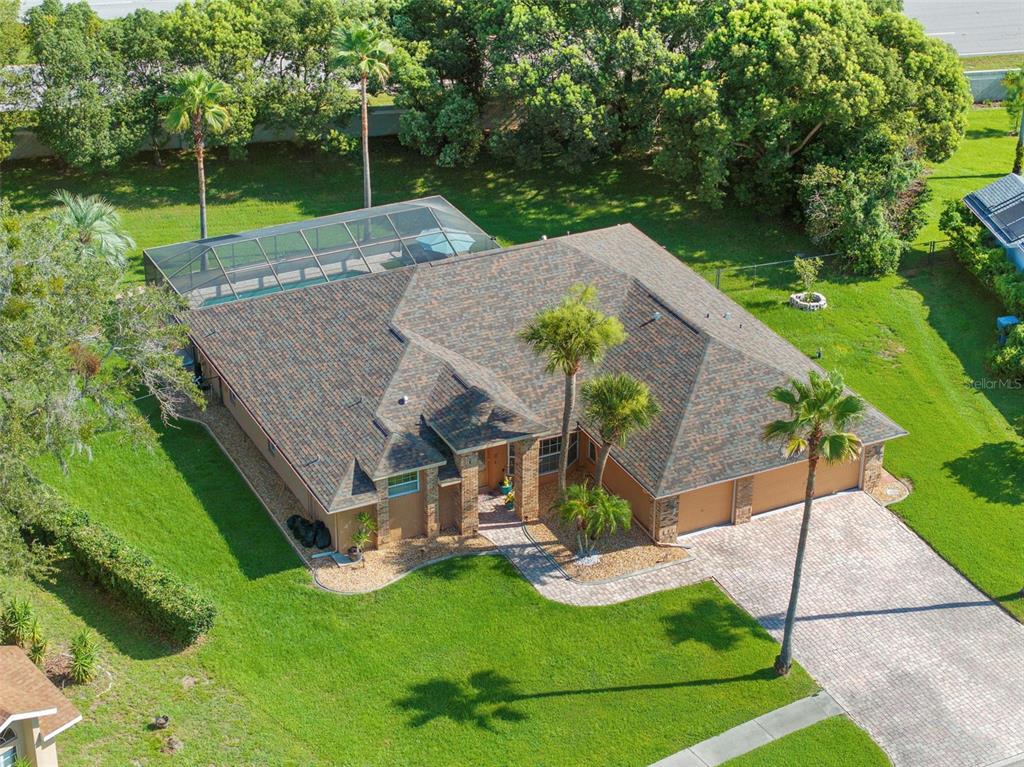 An aerial view shows a single-story house with a shingled roof and a screened pool — 14207 CORNEWALL LANE, SPRING HILL, FL