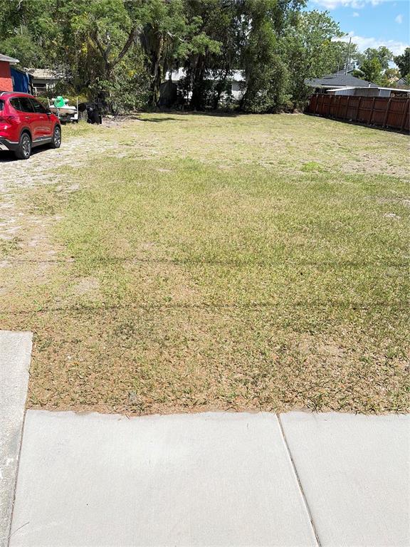 A vacant, grassy residential lot features a concrete sidewalk in the foreground and a red car — 3013 KILGORE STREET, ORLANDO, FL
