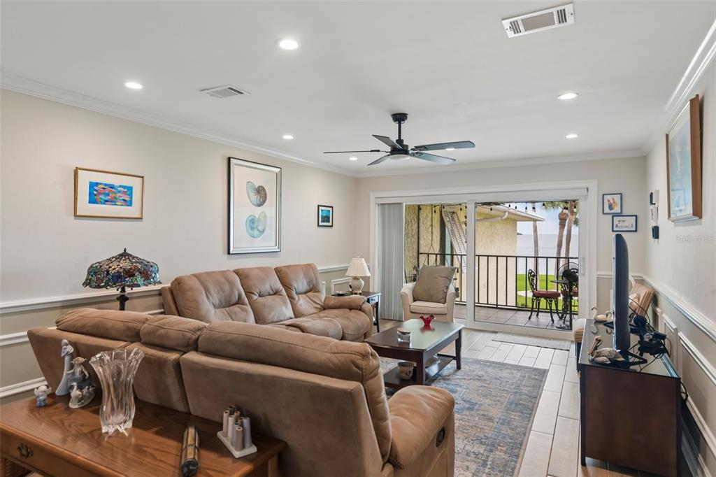 A living room features a brown sectional sofa, a coffee table, and sliding glass balcony doors — 7300 SUNSHINE SKYWAY LANE UNIT 206, ST PETERSBURG, FL