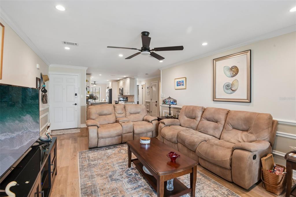 A living room features a brown reclining sofa and loveseat, a coffee table, and wood flooring — 7300 SUNSHINE SKYWAY LANE UNIT 206, ST PETERSBURG, FL