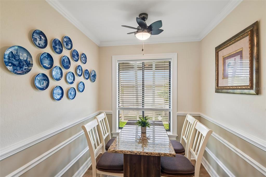 A dining area features a granite-topped table, four chairs, a ceiling fan, and blue decorative plates — 7300 SUNSHINE SKYWAY LANE UNIT 206, ST PETERSBURG, FL