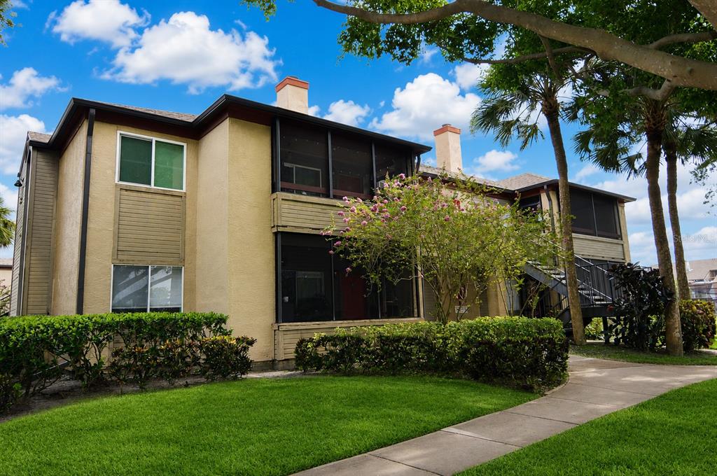 A two-story apartment building with tan stucco walls, screened balconies, and a paved walkway — 10263 GANDY BOULEVARD N UNIT 2407, ST PETERSBURG, FL
