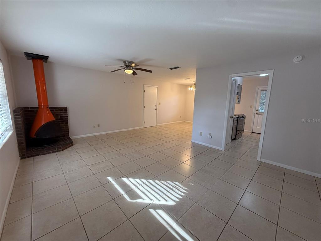 A living room features light tile flooring, a bright orange fireplace, and an adjacent kitchen — 3146 NW 46TH AVENUE, GAINESVILLE, FL
