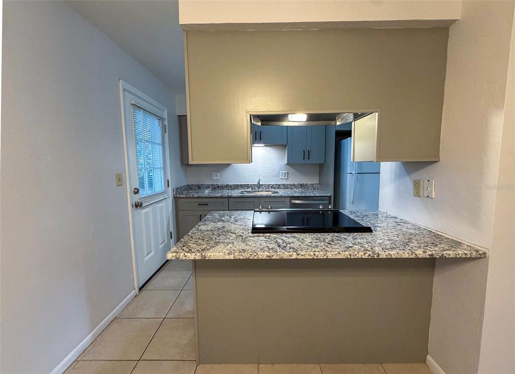 A kitchen features granite countertops, gray cabinets, a glass cooktop, and a door to the outside — 3146 NW 46TH AVENUE, GAINESVILLE, FL