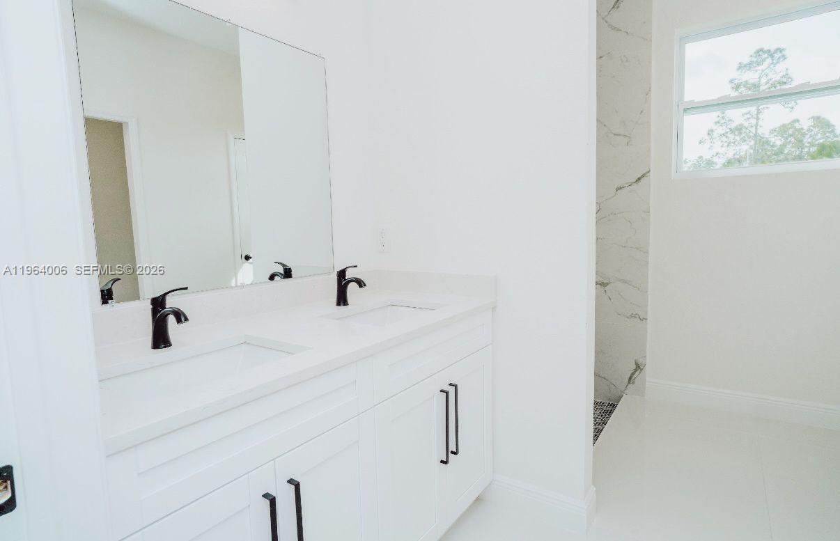 A modern bathroom features a white double vanity with black faucets and a tiled shower — 4405 E 7th, Lehigh Acres FL 33972, LEHIGH ACRES, FL
