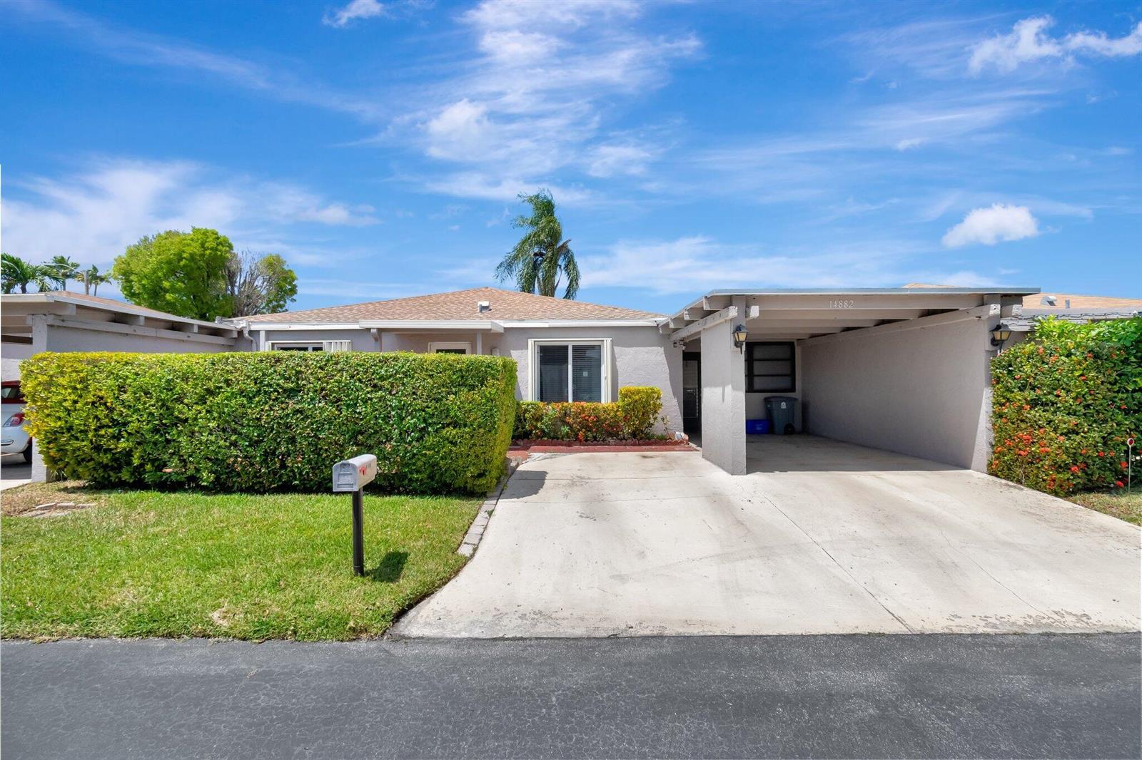 A single-story house with a concrete driveway, a carport, and a large front hedge — 14882 Wildflower Lane, Delray Beach FL 33446, DELRAY BEACH, FL