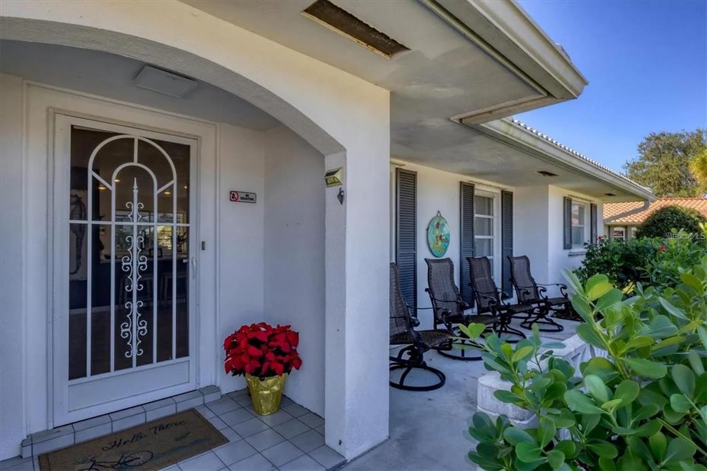 A covered front porch features a white door with a decorative screen and rocking chairs — 2410 CASS STREET, SARASOTA, FL