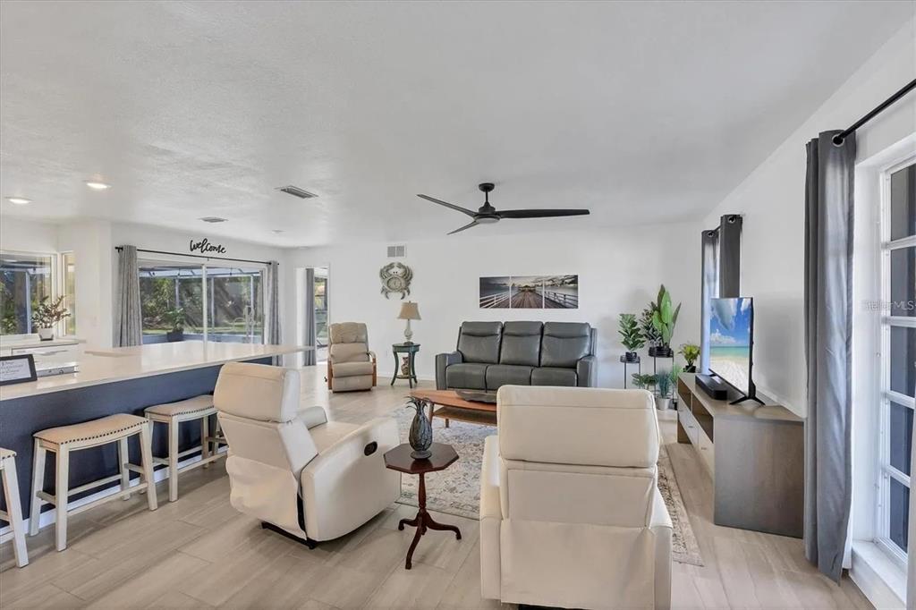 A living room features a gray sofa, two white recliners, and a kitchen island — 2410 CASS STREET, SARASOTA, FL