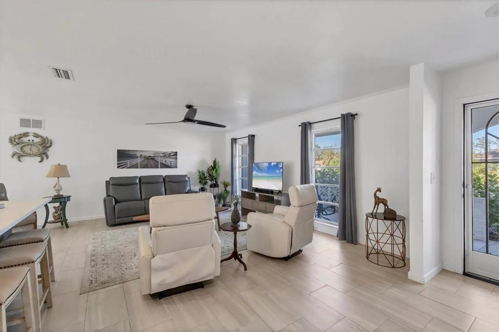 A living room with light tile flooring, a gray sofa, and two white recliners — 2410 CASS STREET, SARASOTA, FL