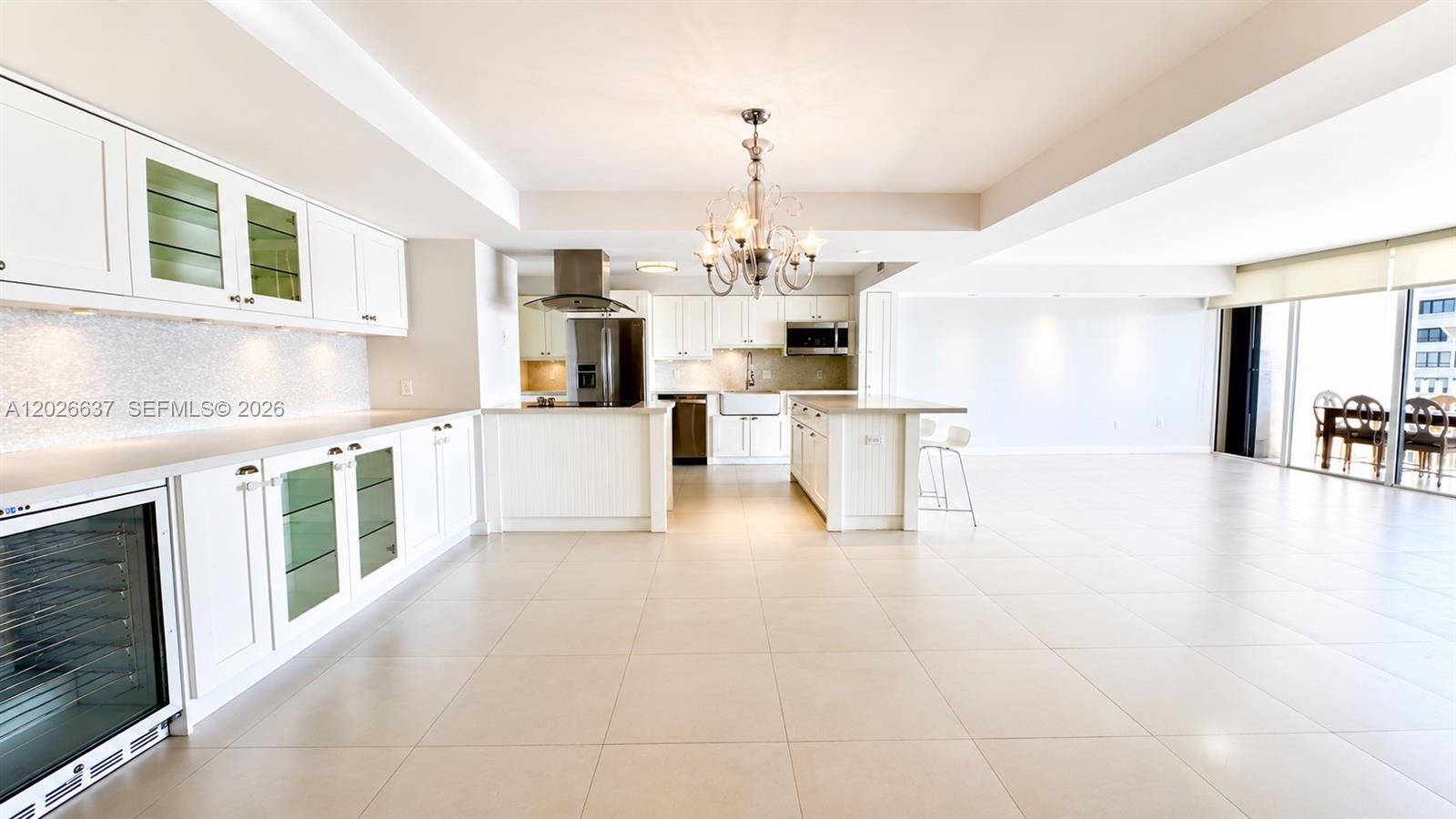 A bright, open-concept kitchen features white cabinetry, a large island, and light tile flooring — 2 Grove Isle Dr # B1706, Miami FL 33133, MIAMI, FL