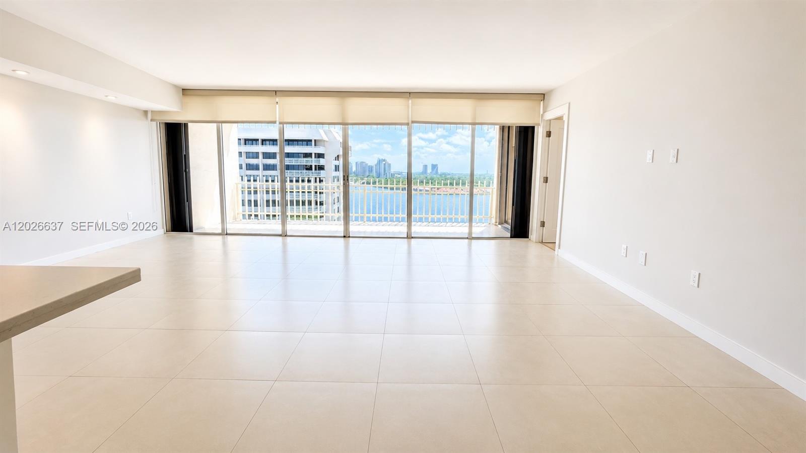 An empty room with large windows overlooking a body of water and city buildings — 2 Grove Isle Dr # B1706, Miami FL 33133, MIAMI, FL