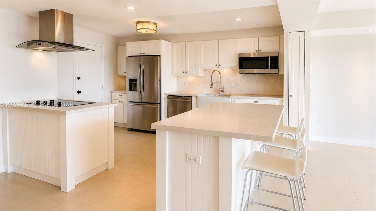 A modern kitchen features white cabinetry, stainless steel appliances, and a central island with seating — 2 Grove Isle Dr # B1706, Miami FL 33133, MIAMI, FL