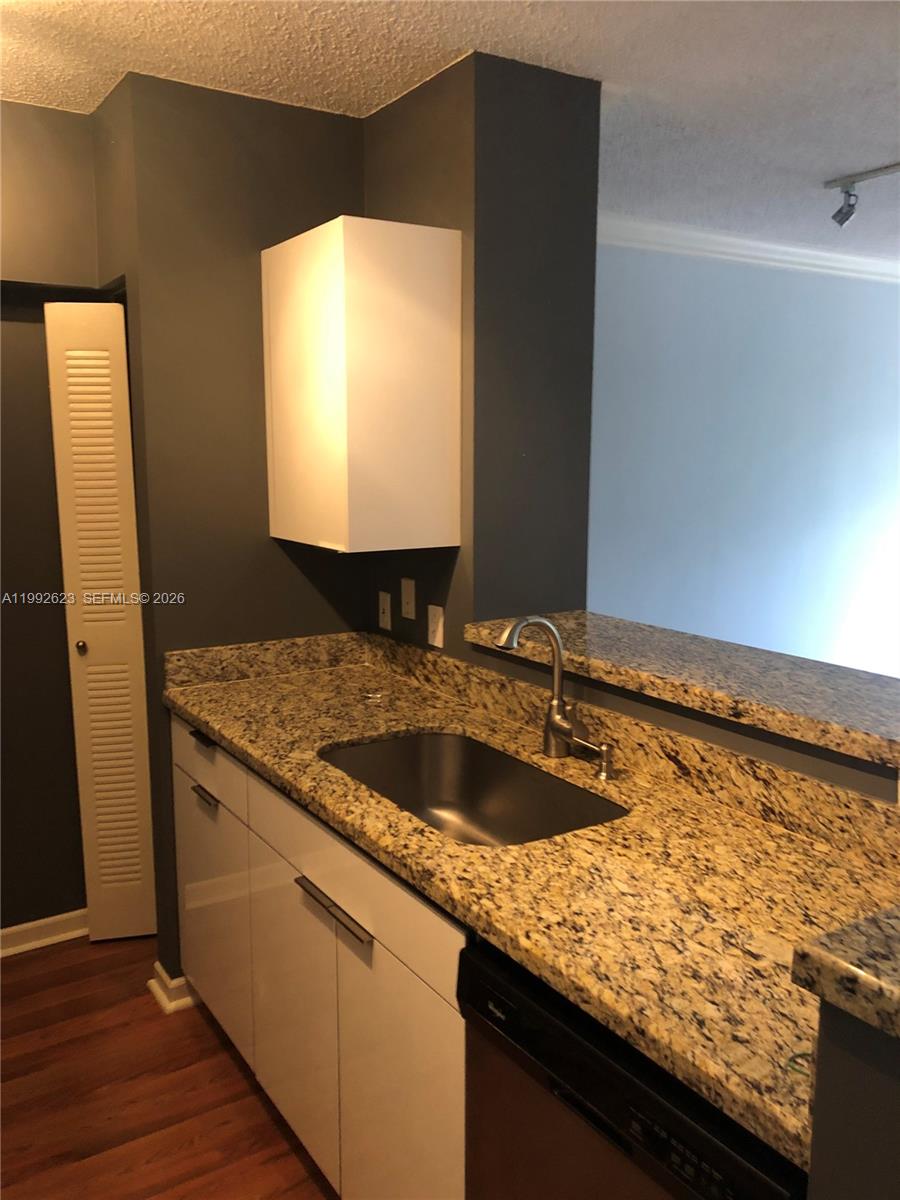 A kitchen features white cabinets, granite countertops, a stainless steel sink, and dark gray walls — 1900 Van Buren St # 411B, Hollywood FL 33020, HOLLYWOOD, FL