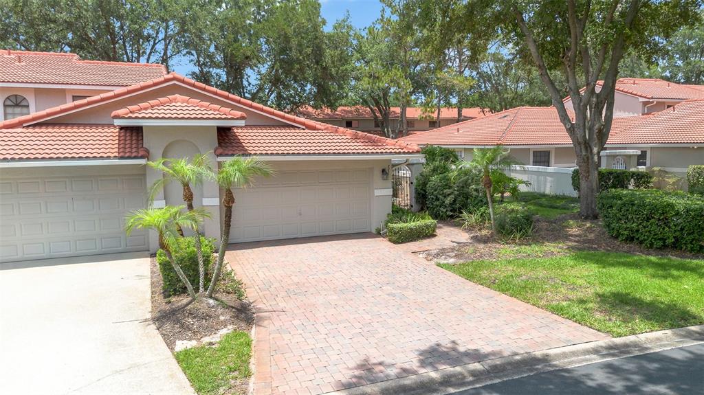 A residential exterior view showing a paved driveway, a garage, and a tiled roof — 8237 BREEZE COVE LANE, ORLANDO, FL