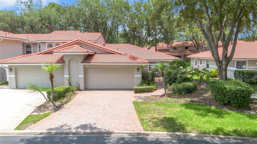 A single-story house with a tiled roof, brick driveway, and attached garage in a neighborhood — 8237 BREEZE COVE LANE, ORLANDO, FL