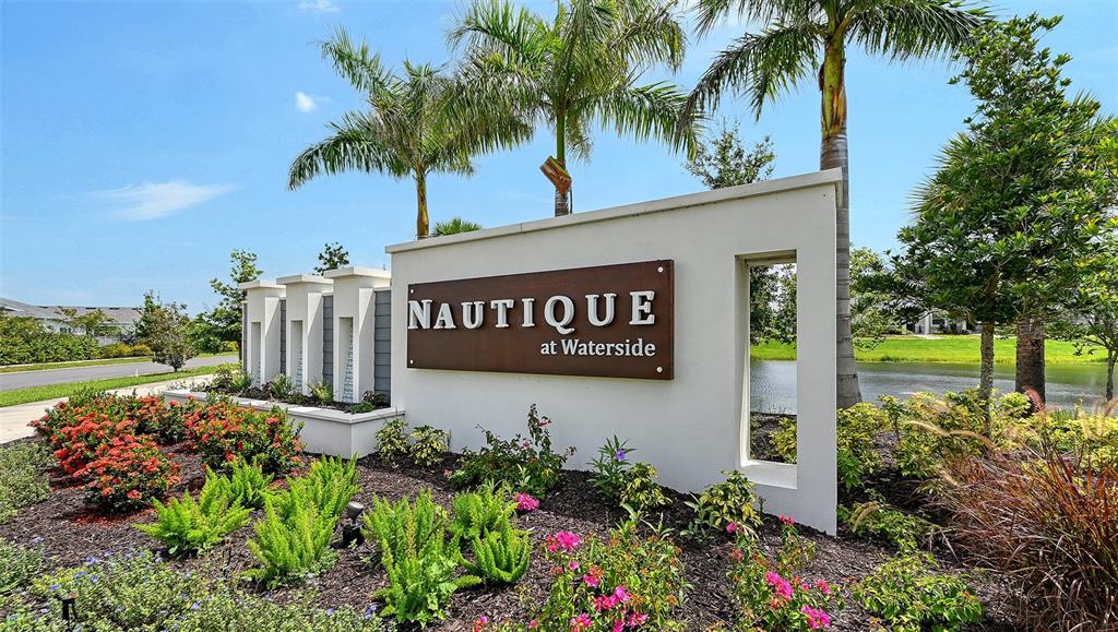 A white monument sign for Nautique at Waterside stands in a landscaped garden with palms — 1763 SPREADER LANE, SARASOTA, FL