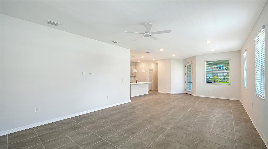 An open-concept living area features light gray tile flooring, white walls, and a ceiling fan — 1763 SPREADER LANE, SARASOTA, FL