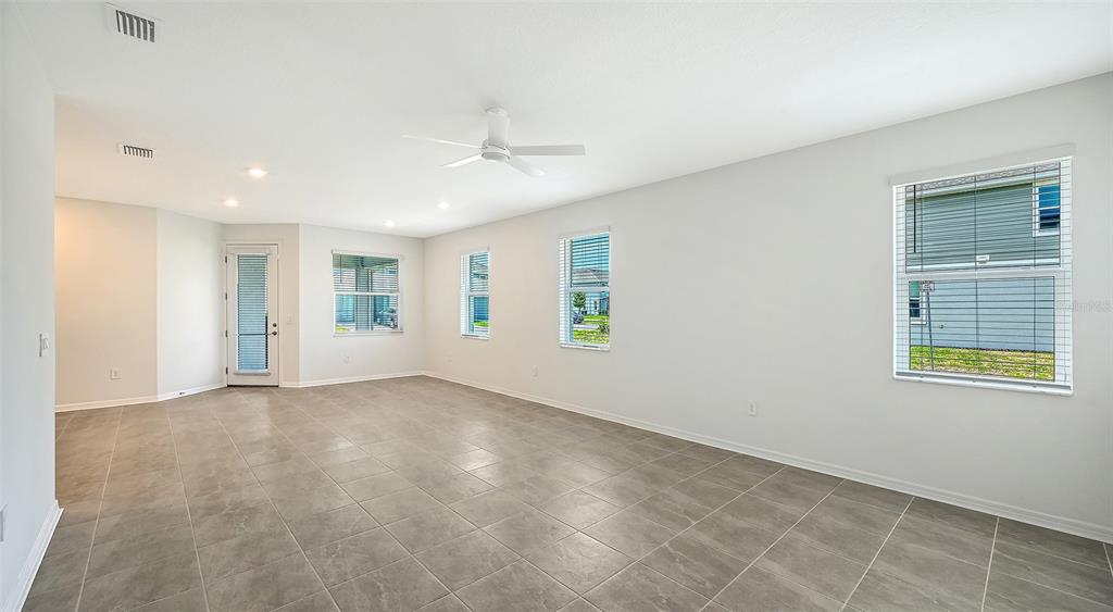 An empty living room features light gray tile flooring, white walls, and a ceiling fan — 1763 SPREADER LANE, SARASOTA, FL
