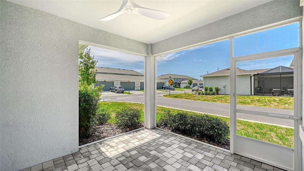 A covered patio with a ceiling fan overlooks a residential street and neighboring houses — 1763 SPREADER LANE, SARASOTA, FL