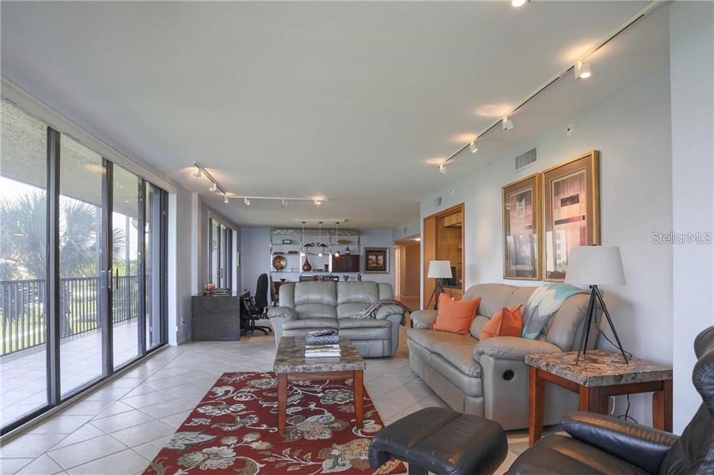 A living room features tile floors, a red patterned rug, and sliding glass balcony doors — 1925 GULF OF MEXICO DRIVE UNIT 309, LONGBOAT KEY, FL