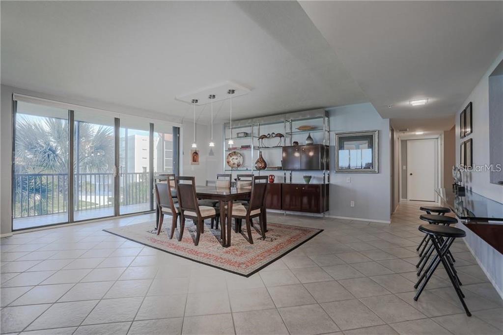 A dining room with tile floors, a wooden table, and a large metal display shelf — 1925 GULF OF MEXICO DRIVE UNIT 309, LONGBOAT KEY, FL