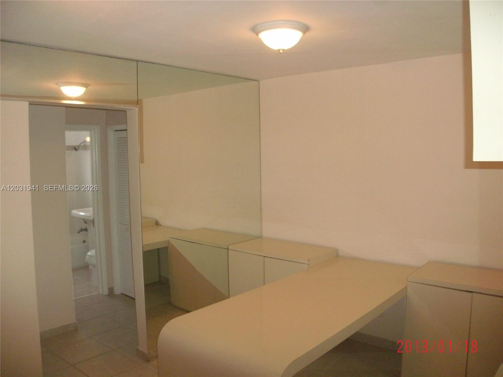 A room features a built-in desk, mirrored wall, and an adjacent bathroom doorway — 2700 NE 135th St # 30, North Miami FL 33181, NORTH MIAMI, FL