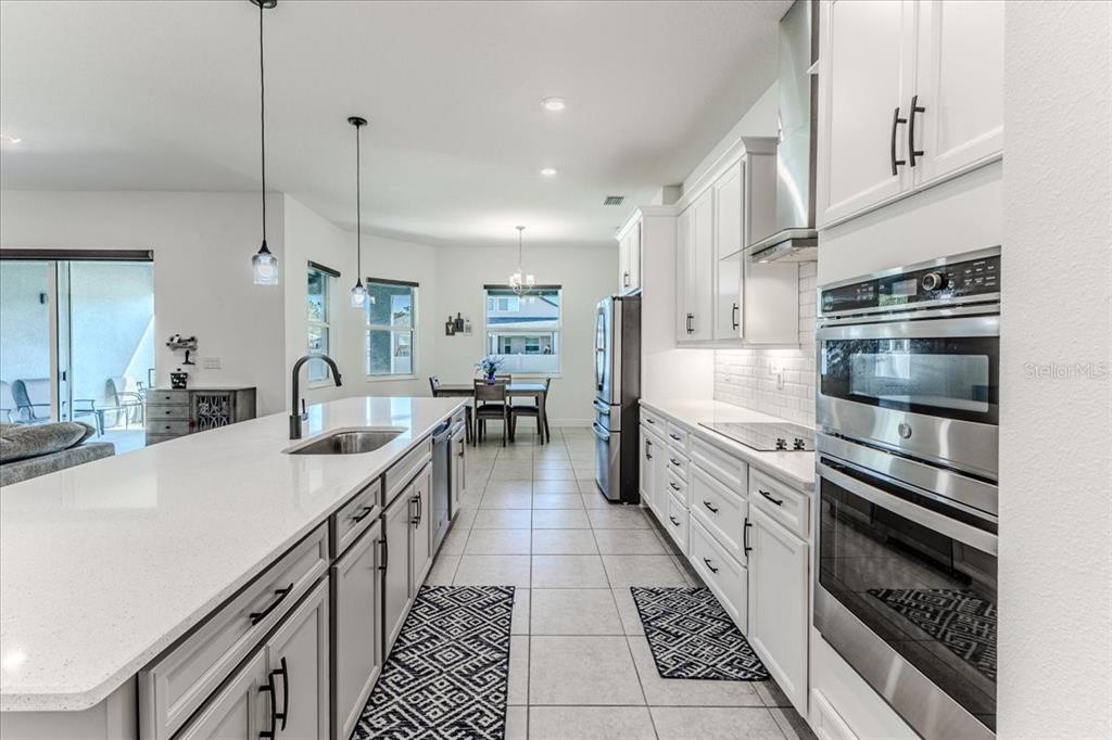 A modern kitchen features white cabinets, quartz countertops, stainless steel appliances, and tile flooring — 1252 KELSA ANNE DRIVE, SPRING HILL, FL