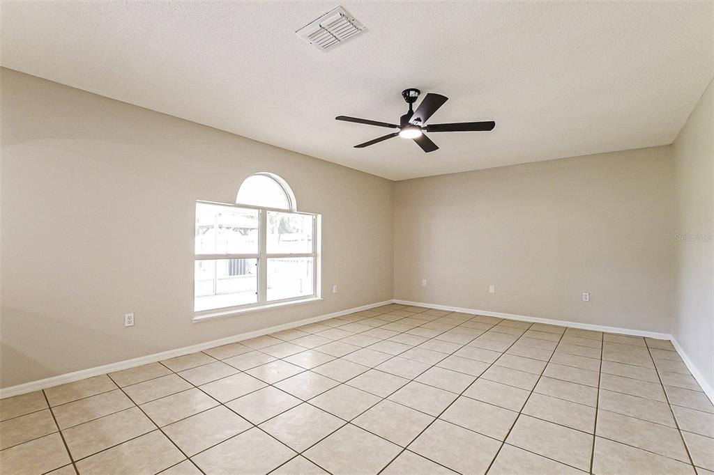 An empty room with beige walls, tile flooring, and a ceiling fan — 10019 DEAN CHASE BOULEVARD, ORLANDO, FL