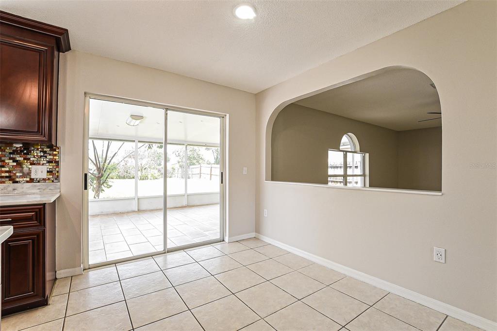 A dining area with tile floors, a sliding glass door, and an arched wall opening — 10019 DEAN CHASE BOULEVARD, ORLANDO, FL