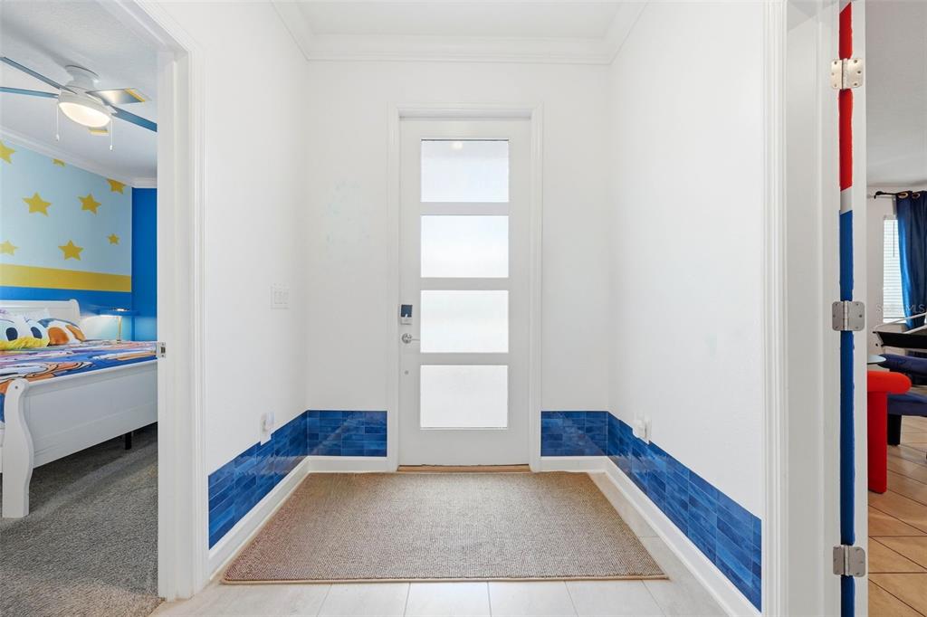 An entryway with white walls, blue tiled wainscoting, a tan rug, and a glass-paneled door — 4189 PARAGRAPH DRIVE, KISSIMMEE, FL