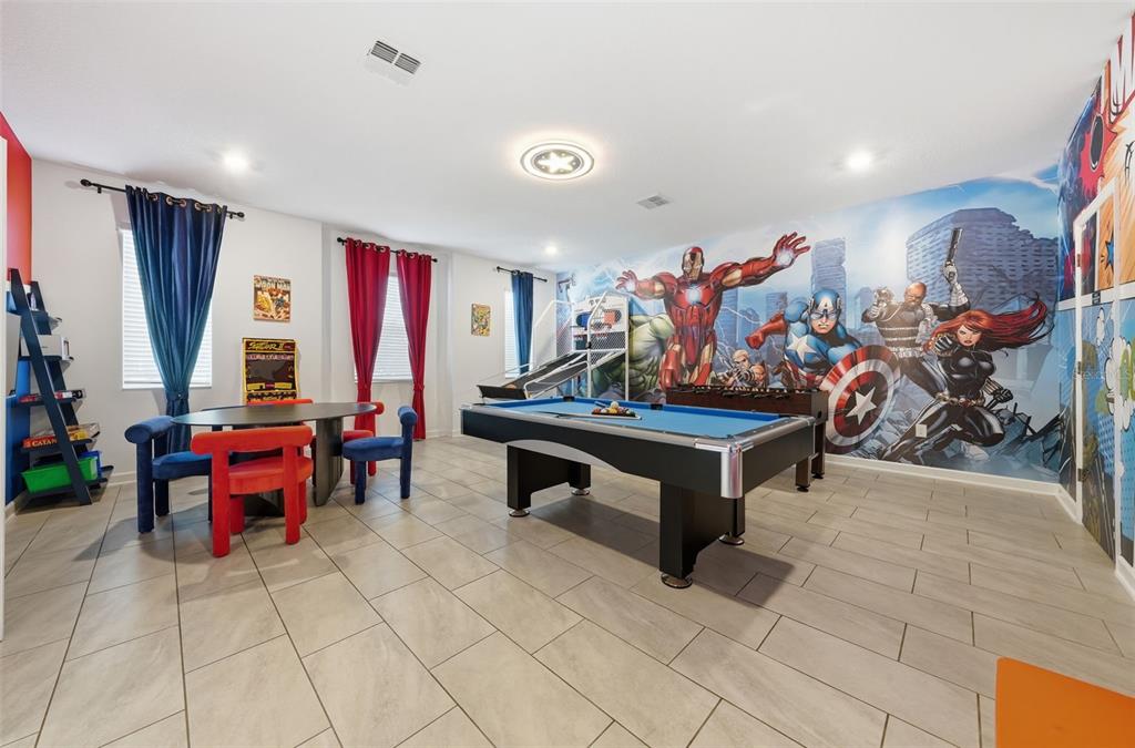 A game room features a pool table, a Marvel-themed wall mural, and a dining area — 4189 PARAGRAPH DRIVE, KISSIMMEE, FL