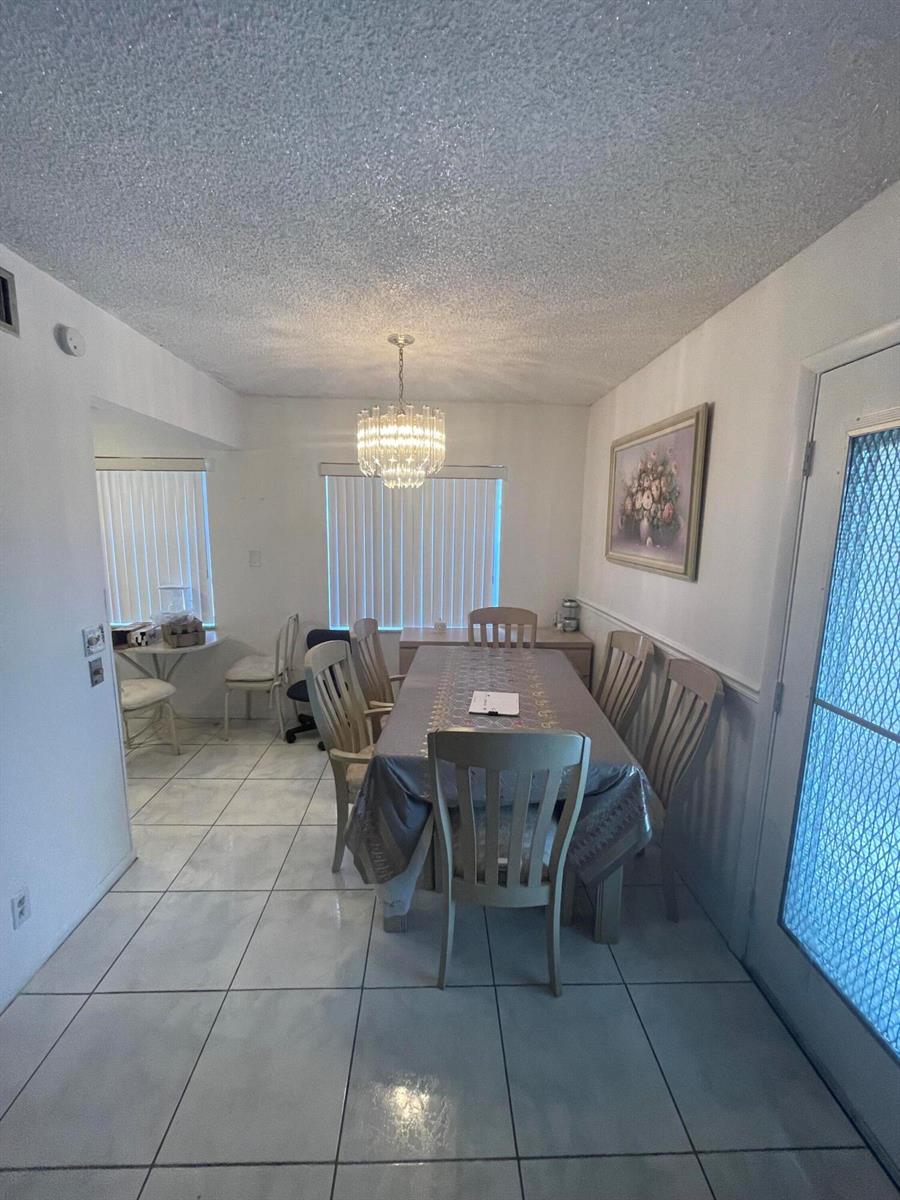 A dining room features a chandelier, a table with chairs, and tiled flooring — 186 Flanders D # 186, Delray Beach FL 33484, DELRAY BEACH, FL