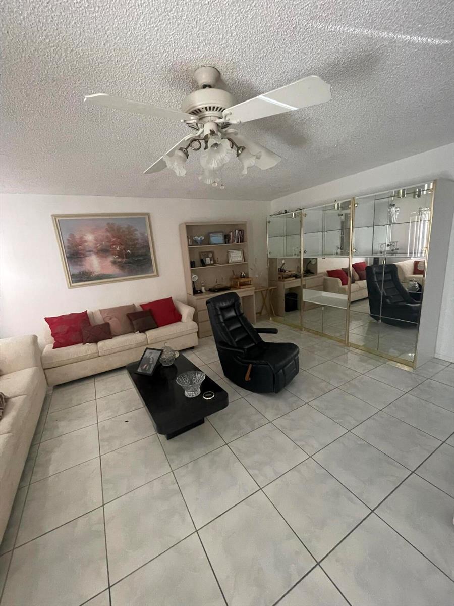A living room features light tile floors, a ceiling fan, a sofa, and mirrored cabinets — 186 Flanders D # 186, Delray Beach FL 33484, DELRAY BEACH, FL