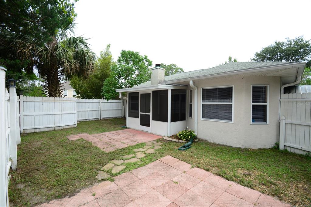 A backyard features a screened-in porch, a paved patio, and a white vinyl privacy fence — 90 SLEEPY HOLLOW TRAIL, PALM COAST, FL