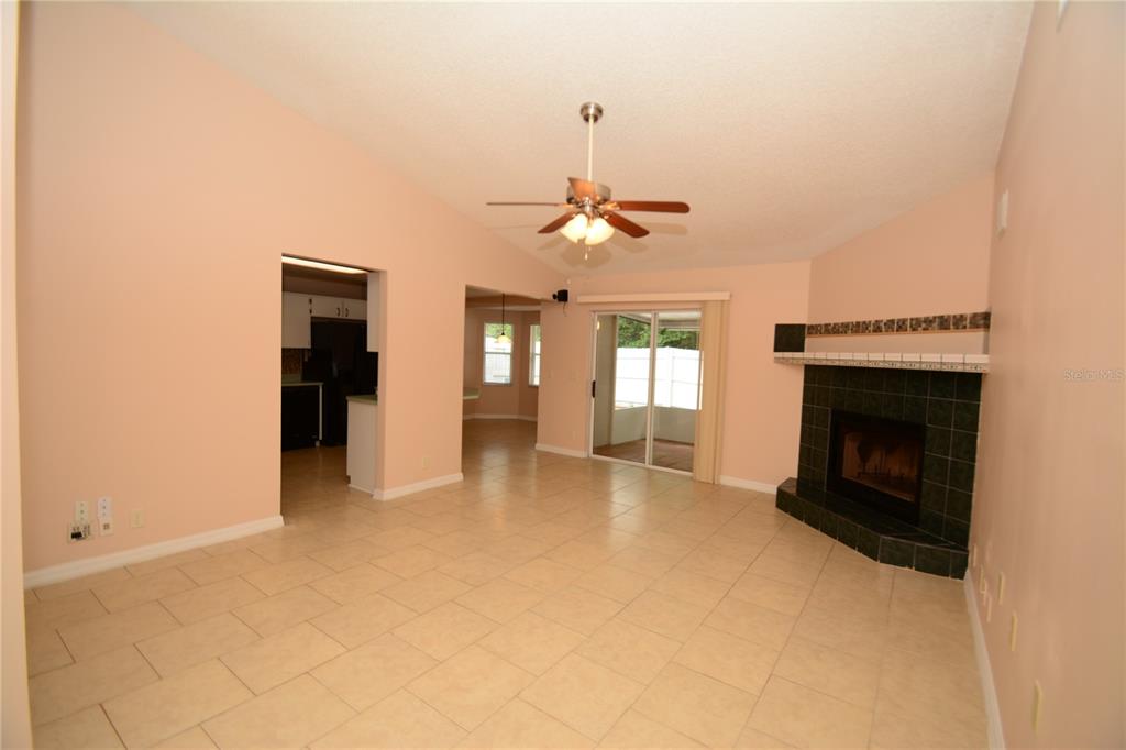 A living room with tile flooring, a corner fireplace, and a ceiling fan — 90 SLEEPY HOLLOW TRAIL, PALM COAST, FL