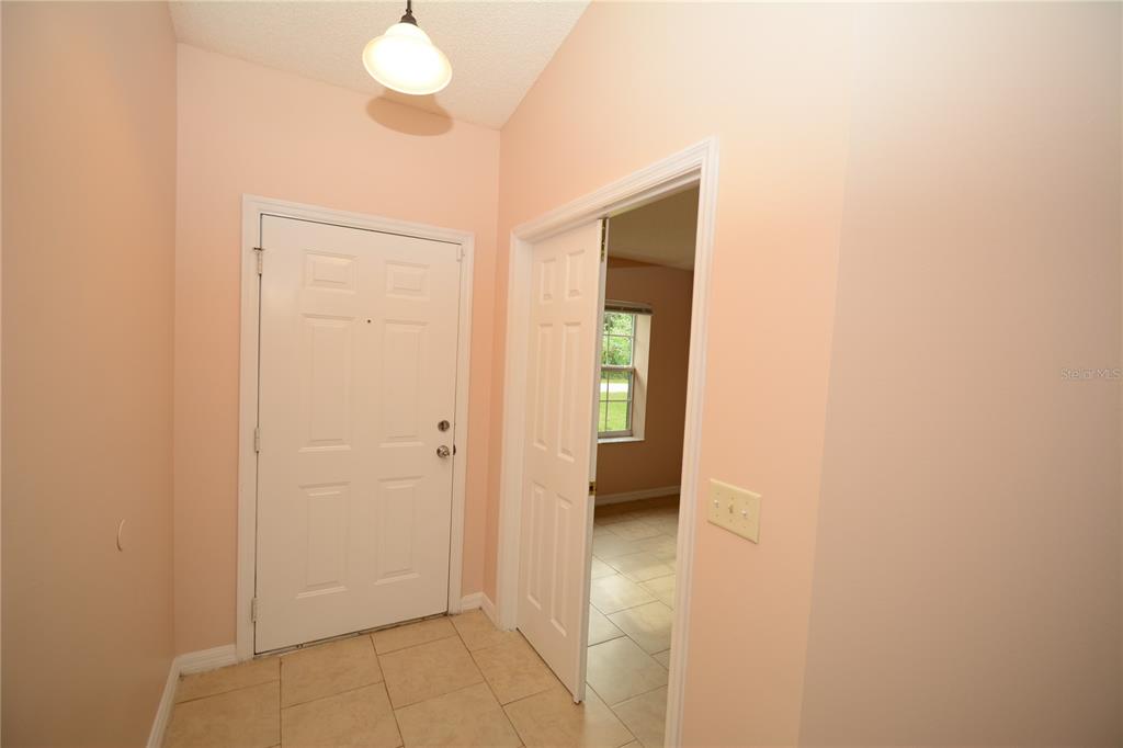 An entryway with light-colored tile flooring, a white front door, and a doorway to another room — 90 SLEEPY HOLLOW TRAIL, PALM COAST, FL